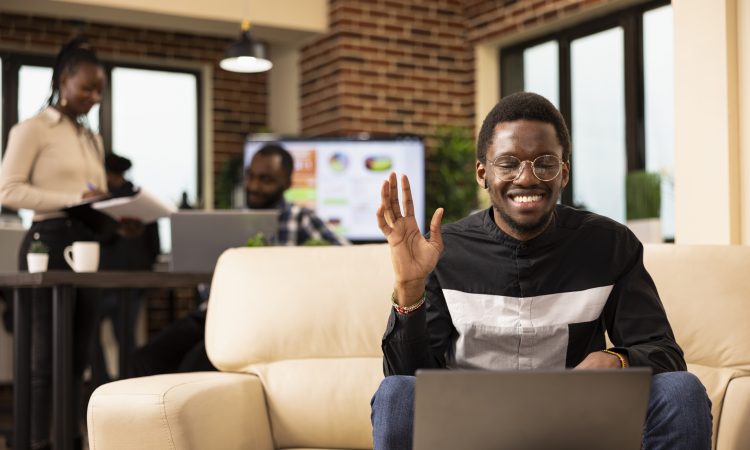 Black man waving towards laptop screen
