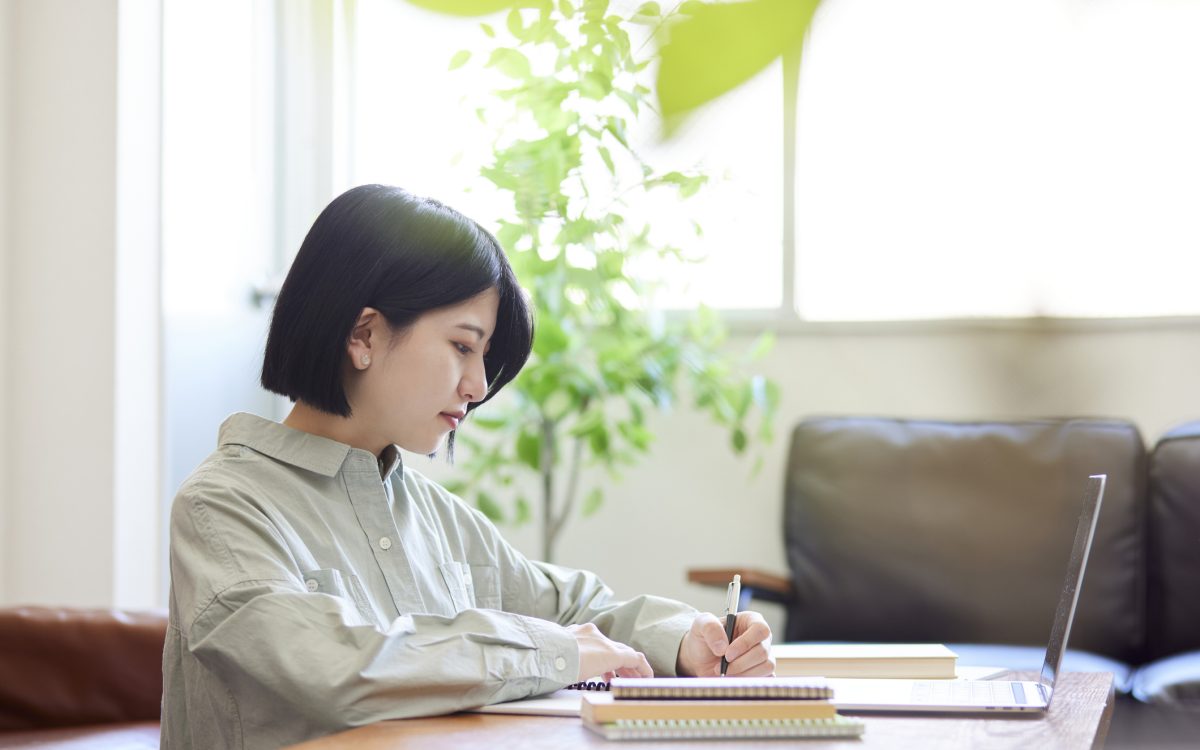Young Japanese woman studying online in the living room