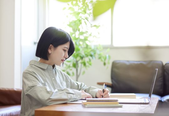 Young Japanese woman studying online in the living room