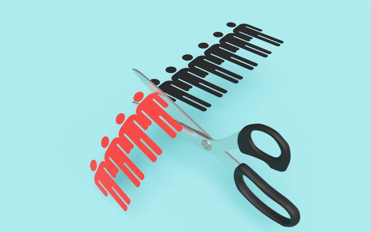 Scissors cutting a paper craft of a row of human shaped outline on blue background. Illustration of the concept of layoff and downsizing of staff