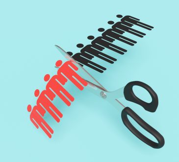 Scissors cutting a paper craft of a row of human shaped outline on blue background. Illustration of the concept of layoff and downsizing of staff