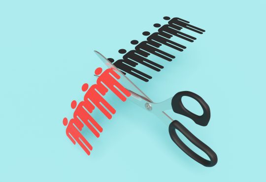 Scissors cutting a paper craft of a row of human shaped outline on blue background. Illustration of the concept of layoff and downsizing of staff