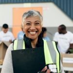 Woman, clipboard and manager in charity, volunteer and organizer for outreach program, smile and portrait. Happy senior person, non profit and support in social responsibility for NGO foundation