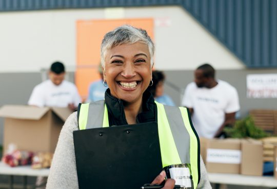 Woman, clipboard and manager in charity, volunteer and organizer for outreach program, smile and portrait. Happy senior person, non profit and support in social responsibility for NGO foundation