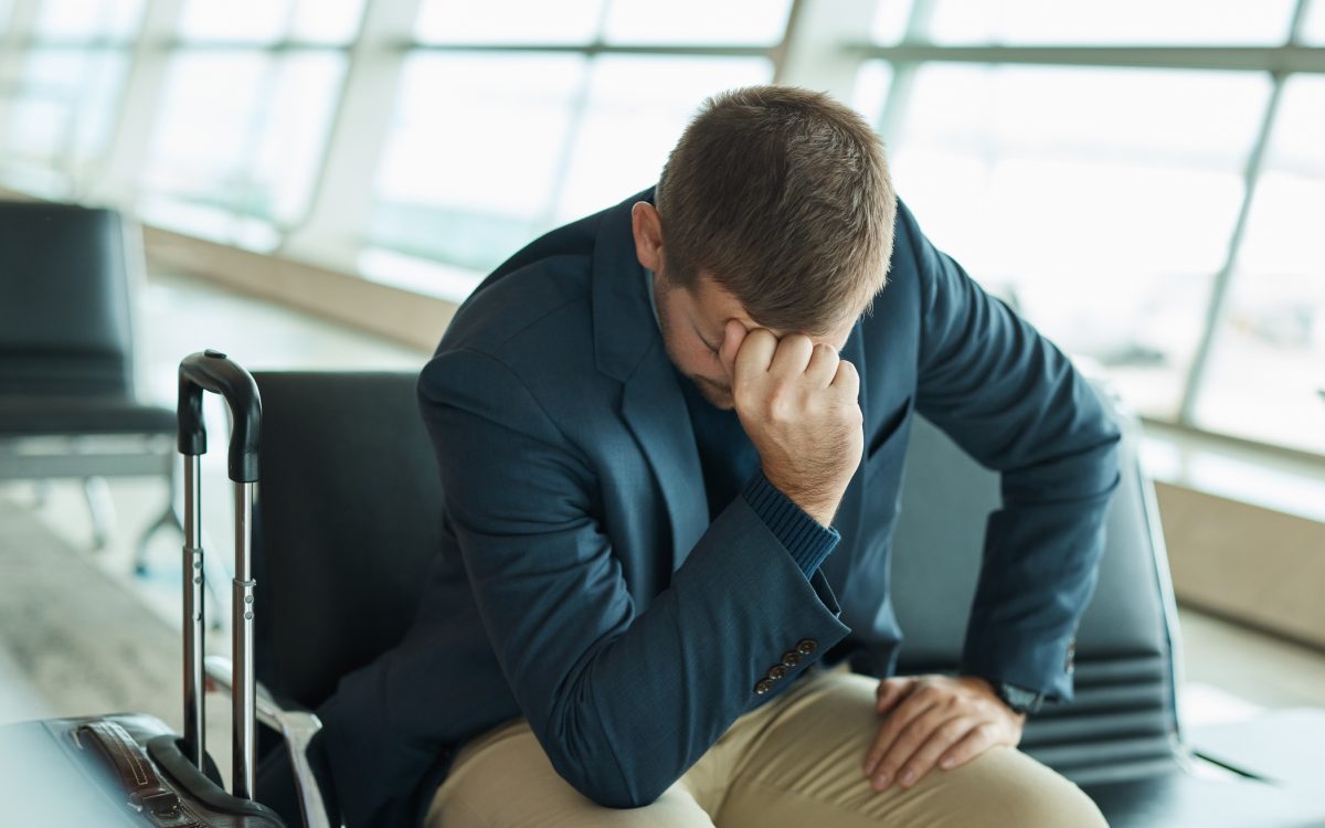Airport, headache and stress man waiting to travel, frustrated and sad for transport delay, crisis or problem. Immigration, anxiety and person thinking, fail or mistake for international flight news