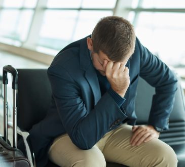 Airport, headache and stress man waiting to travel, frustrated and sad for transport delay, crisis or problem. Immigration, anxiety and person thinking, fail or mistake for international flight news