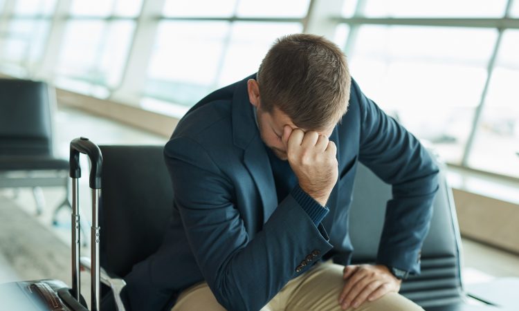 Airport, headache and stress man waiting to travel, frustrated and sad for transport delay, crisis or problem. Immigration, anxiety and person thinking, fail or mistake for international flight news