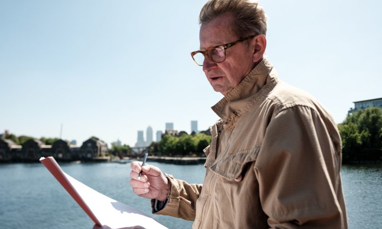 Senior engineer examining architectural plans near the river, with the iconic canary wharf skyline in the background, enjoying a sunny day in vibrant london